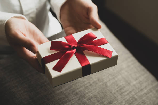 istock Female hand holding present box with red ribbon 1477311766