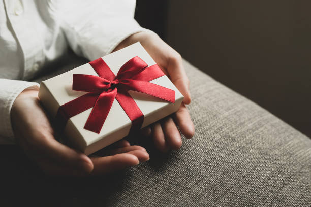 istock Female hand holding present box with red ribbon 1477311767