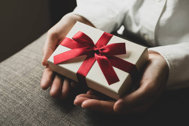 istock Female hand holding present box with red ribbon 1477311768