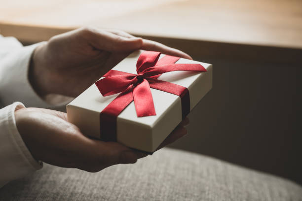 istock Female hand holding present box with red ribbon 1477311773