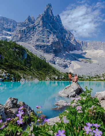 A lone male hiker hiking at Lac Blanc near Chamonix sticks his hands in the air with excitement as he reached the beautiful clear lake