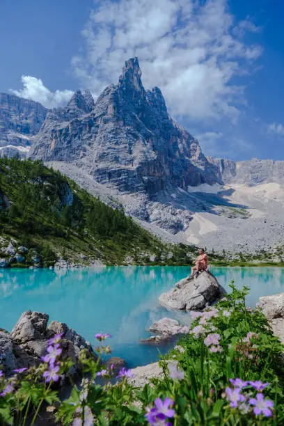 men visiting Lago di Sorapis in the Italian Dolomites, milky blue lake Lago di Sorapis, Lake Sorapis, Dolomites, Italy.