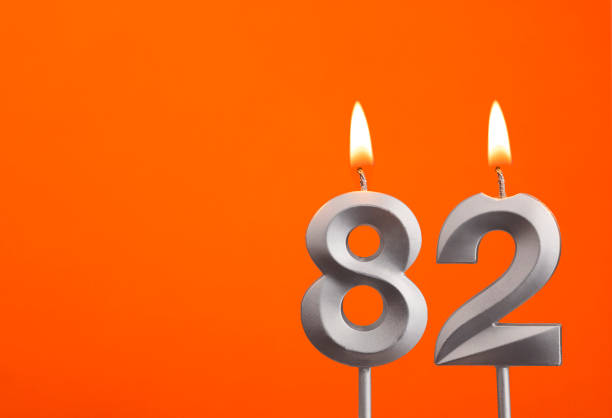istock Number 82 - Silver Anniversary candle on orange background 1477319723