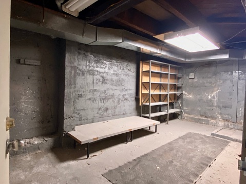Empty basement storage room demolished with cement walls and cement floors
