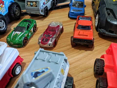 The group of colorful toy car collection on wooden background. Hot Wheels. Top view. Selective focus.