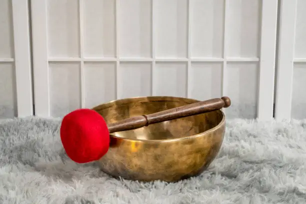 handmade Tibetan singing bowl with a mallet on a fluffy rug, sound therapy for healing, relaxation and meditation