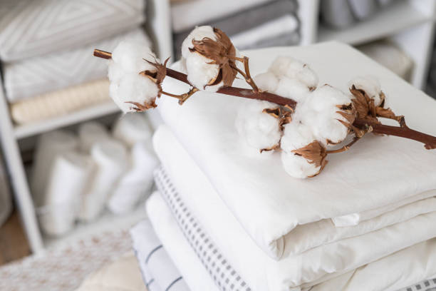 Cotton branch with pile of folded bed sheets and blankets stock photo