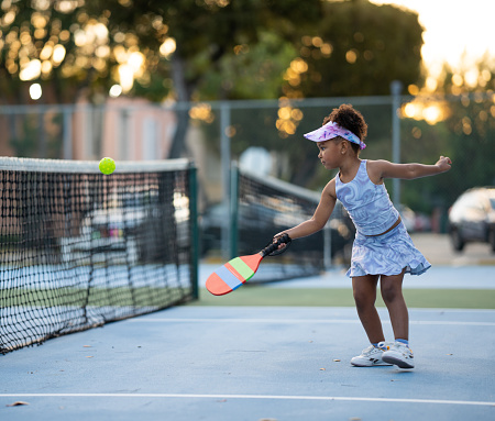 Little girl playing pickleball returning a serve