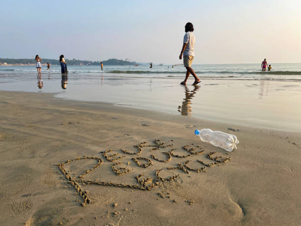 썰물 때 모래 사장에 씻겨 내려간 파란색 뚜껑이 있는 비어 있고 투명한 플라스틱 물병, 해안의 해양 쓰레기 및 오염, 모래에 새겨진 "재사용", "감소" 및 "재활용"이라는 단어, 친환경 개념, 전경� - goa beach india green 뉴스 사진 이미지