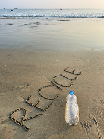 A plastic bottle is washed up on the shore of a beach, with the word 