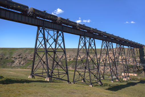 A low angle, looking up at a freight train crossing a long, high trestle bridge.