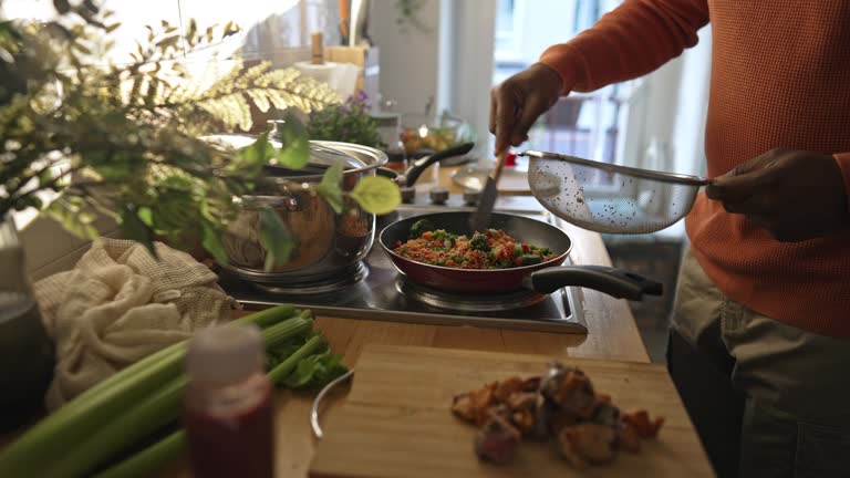 Man preparing quinoa vegetable mix cooked in a frying pan