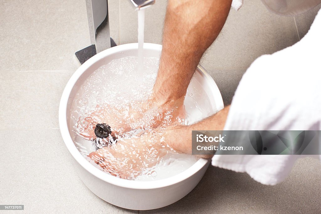 man having hydrotherapy water footbath Man having hydrotherapy water footbath in spa setting Foot Bath Stock Photo