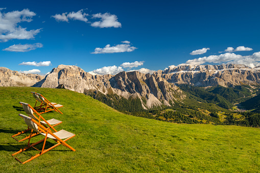 empty sun loungers on green gras high up in the seceda mountains of south tyrol italy on sunny day