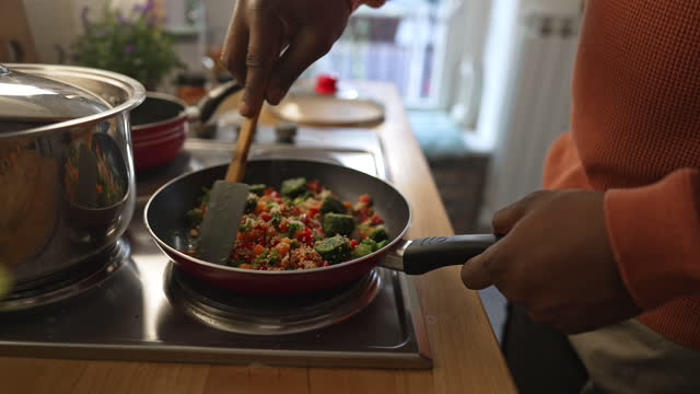 Man preparing quinoa vegetable mix cooked in a frying pan