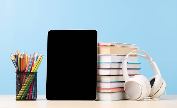 Tablet with colorful pencils and stack of books