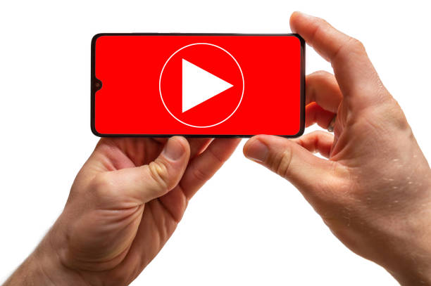 Smartphone is held in hands, on the display of which a play sign appears