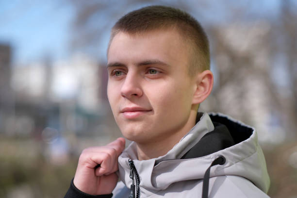 Portrait of a young handsome guy with a short haircut on the street of a spring city close-up on a bright sunny day
