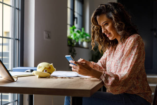 istock Young woman counting coins from a broken piggy bank and using calculator 1477388314