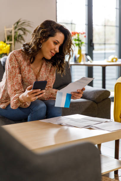 istock Young woman using smart phone when paying her financial bills 1477388559