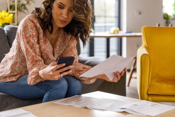 istock Young woman using smart phone when paying her financial bills 1477388586