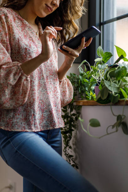 istock Young woman standing by the window, using smart phone 1477389231