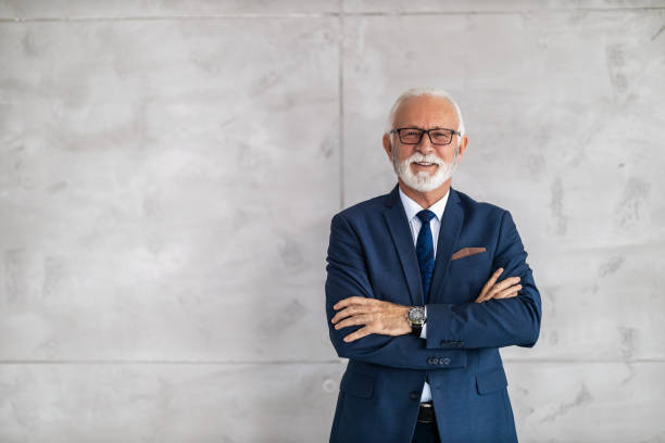 istock Senior businessman posing on gray background, he is smiling at camera 1477391171