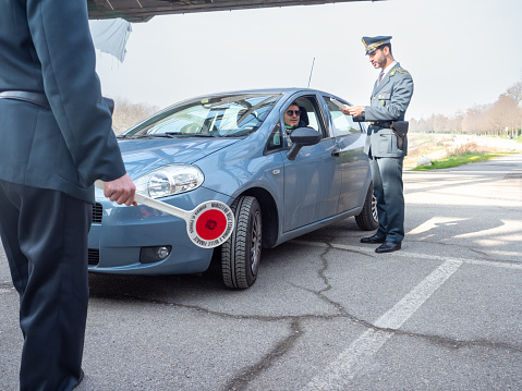 Cremona, Italy - February 2023 two tax police officers in duty near Po river city bridge on the border of Lombardy and Emilia Romagna