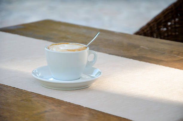 Cappuccino coffee in white cup on wood table.
