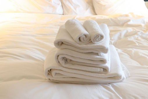 Selective focus on white fresh towels in hotel bed. Room service concept. Closeup white on new bedding and personal hygiene items. Accommodation, hospitality and motel business. Bedroom interior