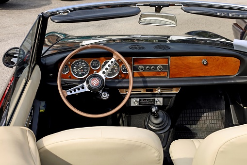 Percoto, Italy. March 19, 2023 . Interior with steering wheel and dash of a Seventies convertible Fiat sports car, during a vintage car gathering.