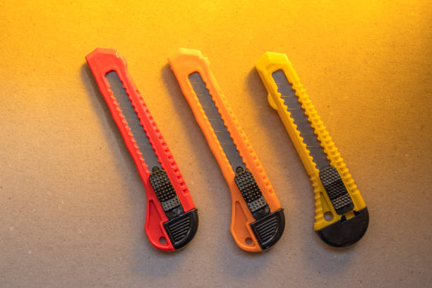 istock Red and orange sharp office stationery knife brown a cardboard cutting blade on a desktop office desk 1477415350