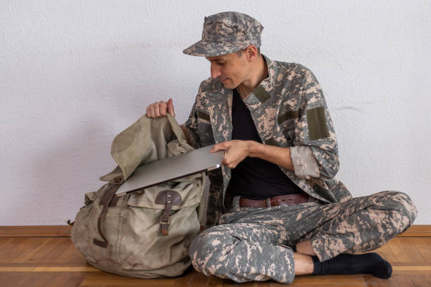istock Busy soldier with backpack using military laptop 1477423405