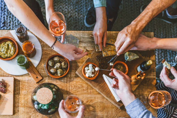 vista superior de un grupo de personas alrededor de una mesa disfrutando de la comida y la amistad - aperitivo fotografías e imágenes de stock