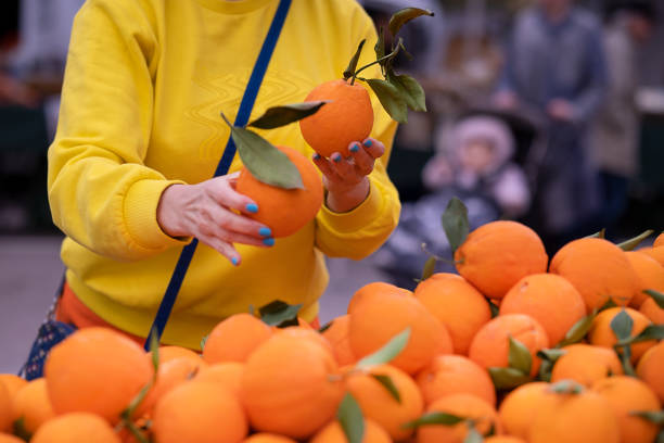 a woman in a yellow jumper buys oranges