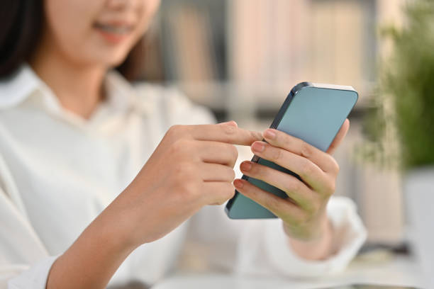 istock Selective focus on hands. Smiling young woman typing massage on her mobile phone while sitting at workplace. 1477427343