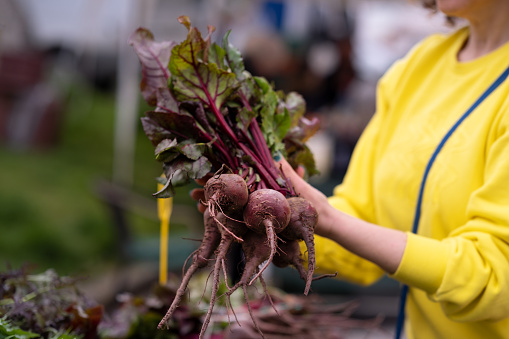 a woman in a yellow jumper buys beets