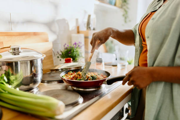프라이팬에서 조리된 퀴노아 야채 믹스를 준비하는 여자 - 요리하기 식품 상태 뉴스 사진 이미지