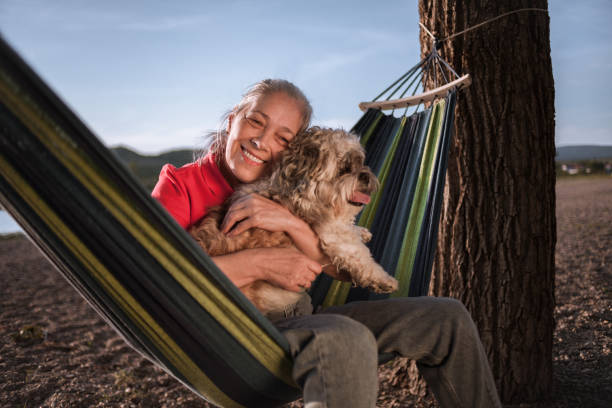 istock Senior woman lying in a hammock and playing with her dog 1477436122