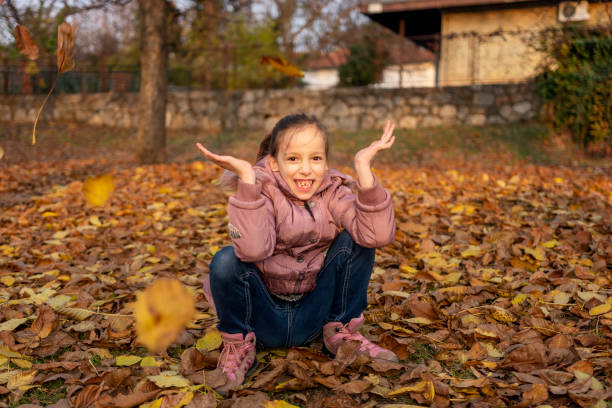 Happy girl having fun while throwing leaves in autumn park