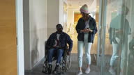 istock Woman showing a new place of work to a man in a wheelchair 1477437406