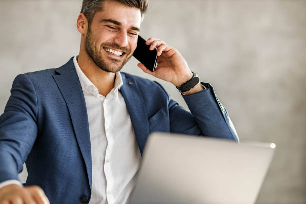 istock Happy businessman talking on cell phone while working on laptop in the office. 1477440856