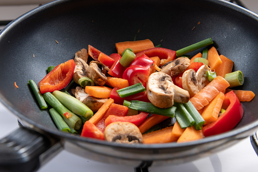 Stirred fried colourful vegetables cooking in a wok.