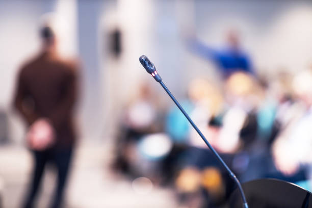 istock Microphone in focus, blurred speaker and audience at workshop, training, business conference or presentation 1477448824