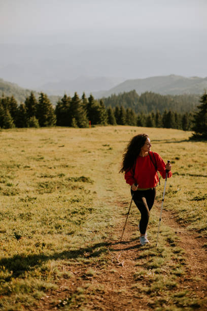 istock Young woman walking with backpack over green hills 1477449157