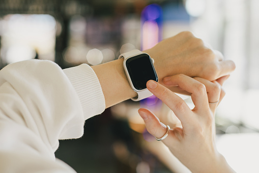 Woman uses a smart watch indoors with soft lighting. Hands only.