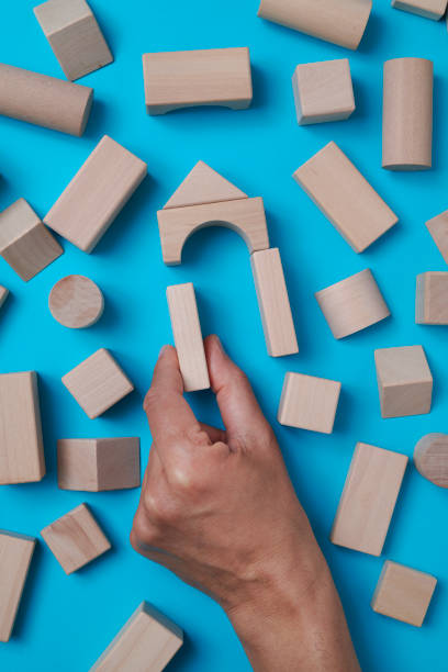man forms a house with building blocks stock photo