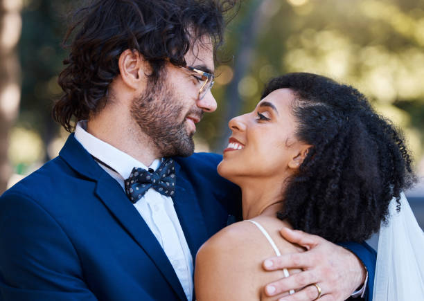 istock Happy couple, love and wedding celebration event together with commitment, care and support. Interracial man and woman at park with trust, marriage partnership and a hug with a smile on their face 1477453622