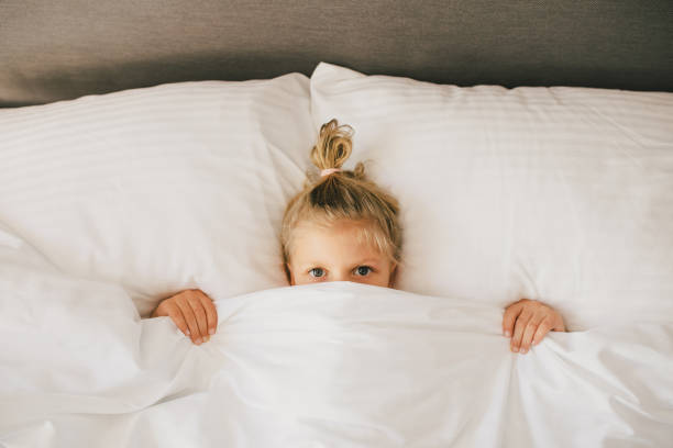 istock Cute little girl having fun lying in bed. 1477456869