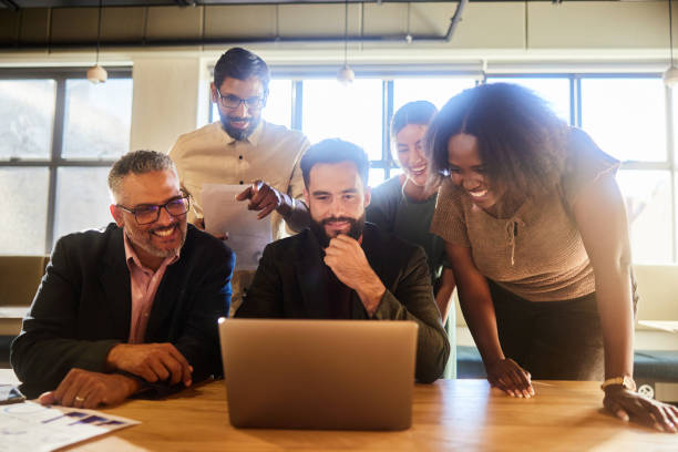 istock Diverse businesspeople laughing over a laptop at an office table 1477457129
